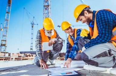 Three Construction Workers Sitting on Concrete at Construction Site, Discussing Stock Photo - Image of protection, coworkers_ 119766226